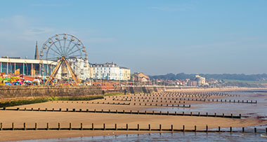 a view of the beach in Bridlington with a Ferris wheel and carnival on the seafront 