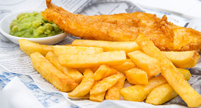 a portion of fish and chips with mushy peas on a newspaper 