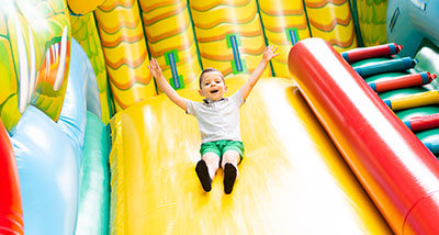a child with his hands in the air sliding down an inflatable slide