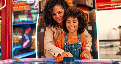 a mother and child playing air hockey together in an arcade