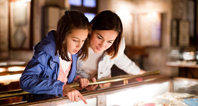 a mother and daughter looking at objects in a museum