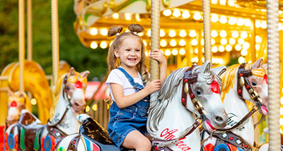 a girl riding a horse figure on a carousel roundabout 